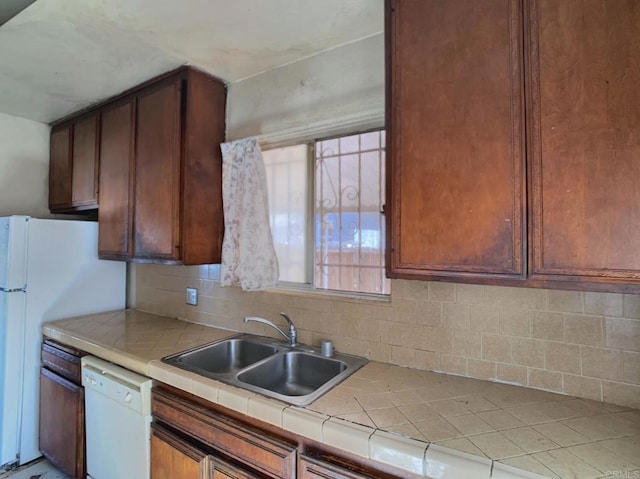 kitchen with decorative backsplash, tile countertops, white appliances, and a sink