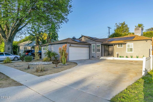 ranch-style home with solar panels, fence, stucco siding, a garage, and driveway