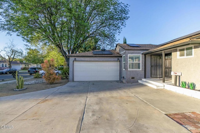 exterior space featuring stucco siding, an attached garage, concrete driveway, and solar panels