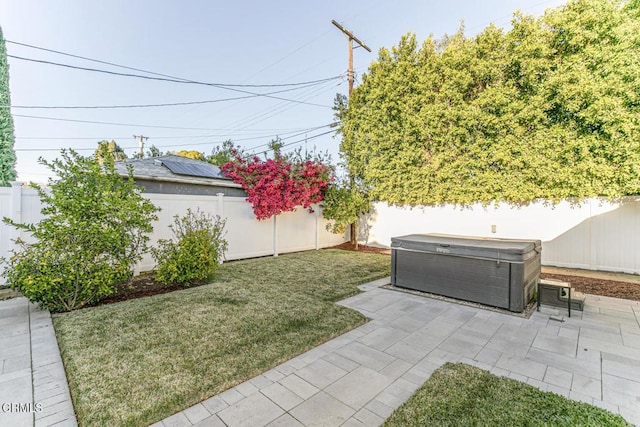 view of yard with a patio area, a fenced backyard, and a hot tub