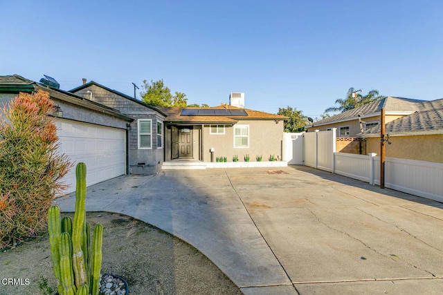 single story home with stucco siding, driveway, roof mounted solar panels, fence, and a garage