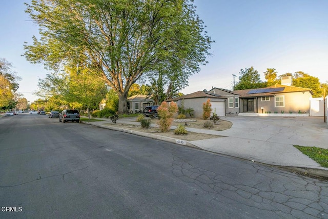 single story home featuring driveway, solar panels, and an attached garage