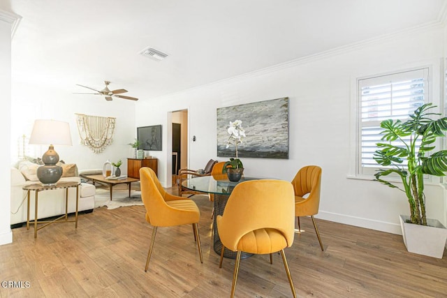 dining area with light wood-style floors, visible vents, and ornamental molding