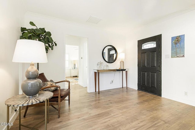 entrance foyer featuring crown molding, wood finished floors, and a wealth of natural light