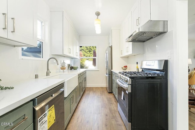 kitchen with under cabinet range hood, light countertops, light wood-style flooring, appliances with stainless steel finishes, and white cabinetry