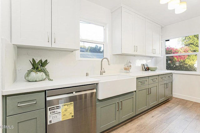 kitchen featuring light wood finished floors, a sink, light countertops, stainless steel dishwasher, and backsplash