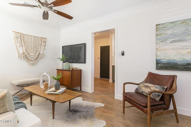 living area featuring ceiling fan, baseboards, wood finished floors, and ornamental molding