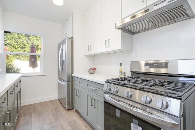 kitchen with light wood-style flooring, gray cabinets, under cabinet range hood, stainless steel appliances, and light countertops