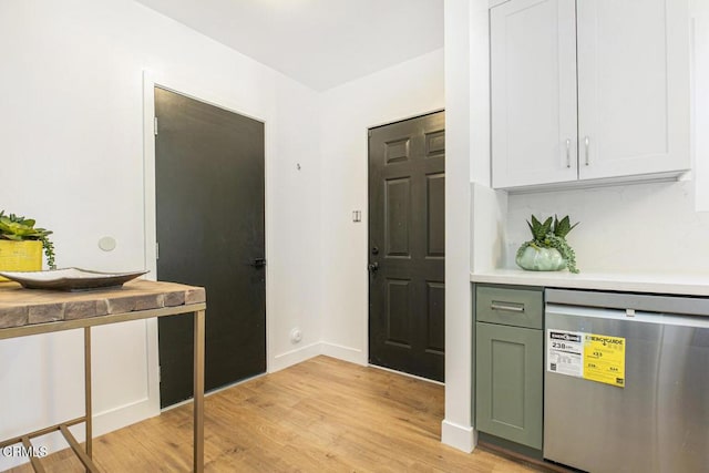 kitchen featuring light wood finished floors, baseboards, light countertops, stainless steel dishwasher, and green cabinetry