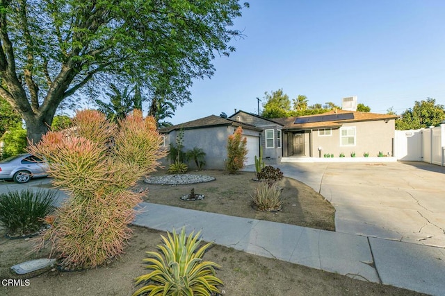 single story home with stucco siding, driveway, fence, a garage, and solar panels