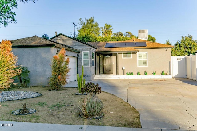 single story home featuring stucco siding, fence, concrete driveway, a garage, and solar panels