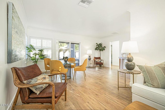 interior space featuring visible vents, baseboards, light wood-style flooring, and crown molding