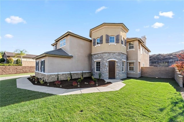 view of front of home featuring stucco siding, stone siding, and a front yard