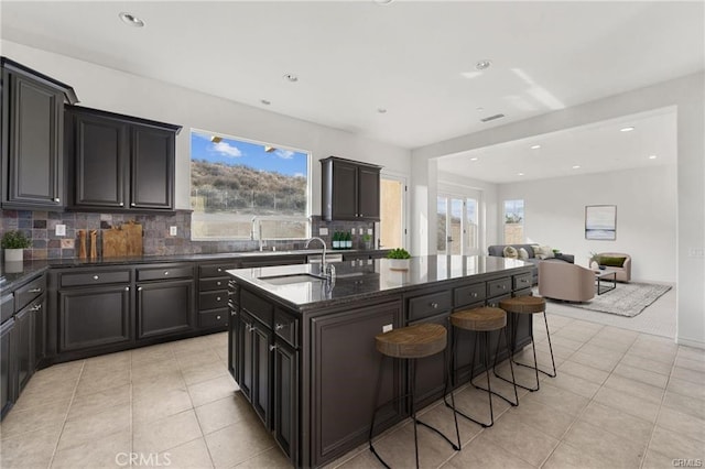 kitchen with a sink, a kitchen bar, plenty of natural light, and an island with sink