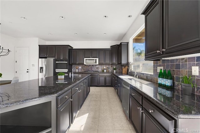 kitchen with tasteful backsplash, dark stone counters, appliances with stainless steel finishes, light tile patterned flooring, and a sink