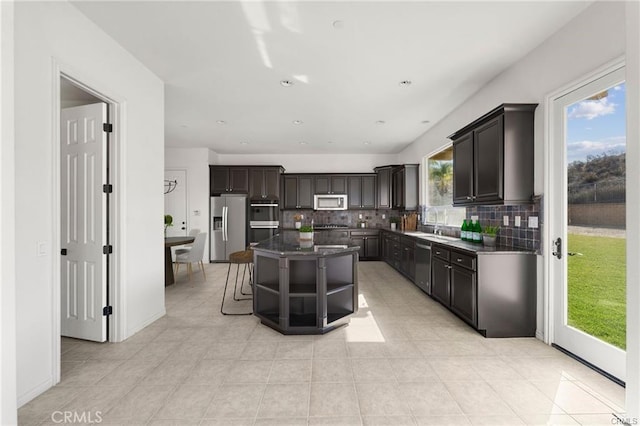 kitchen with light tile patterned floors, a kitchen island, open shelves, stainless steel appliances, and tasteful backsplash