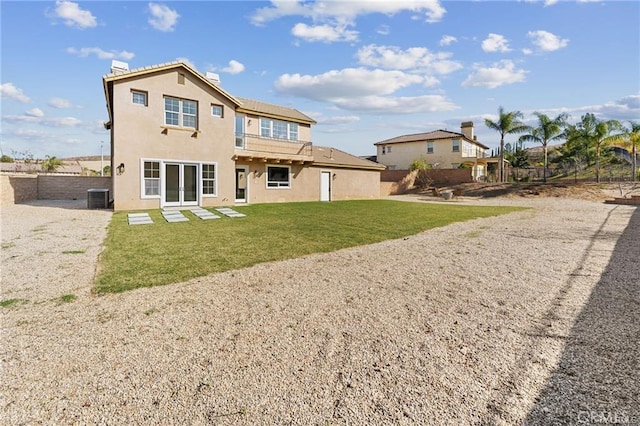 rear view of house featuring cooling unit, fence, a lawn, and stucco siding