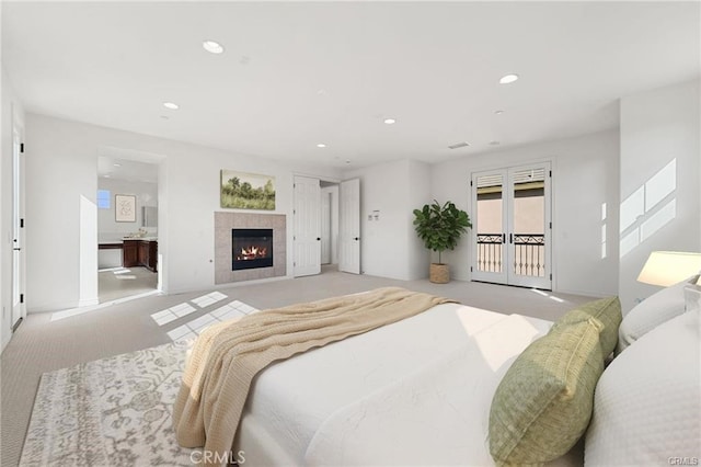 carpeted bedroom featuring recessed lighting, a tile fireplace, access to exterior, french doors, and ensuite bathroom