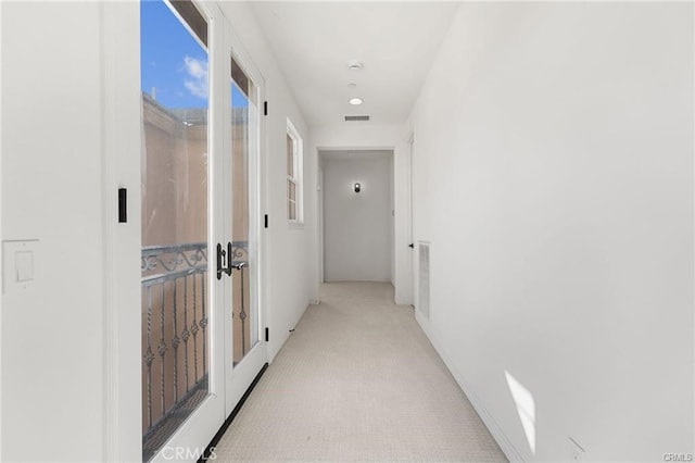 hallway featuring light colored carpet, baseboards, and visible vents