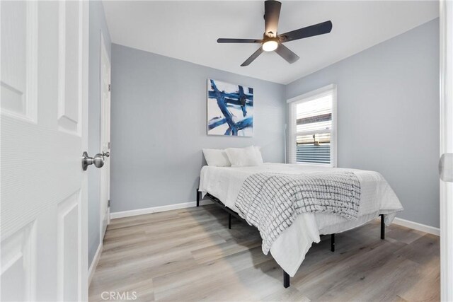 bedroom featuring light wood-style flooring, baseboards, and ceiling fan