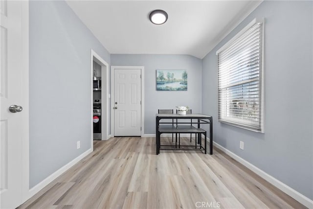 interior space featuring lofted ceiling, baseboards, and light wood-type flooring