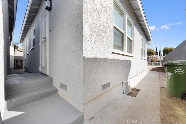 view of side of home featuring crawl space, stucco siding, and fence