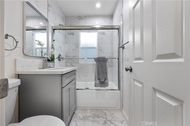 full bath featuring plenty of natural light, marble finish floor, toilet, and bath / shower combo with glass door