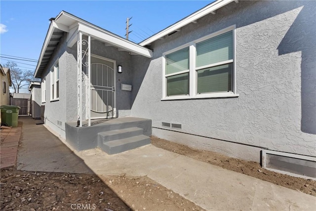 view of front of home featuring crawl space, stucco siding, and fence