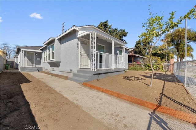 view of front facade with a porch, fence, crawl space, and stucco siding