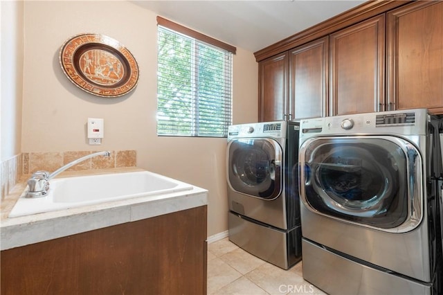 washroom featuring a sink, light tile patterned flooring, cabinet space, and washing machine and clothes dryer