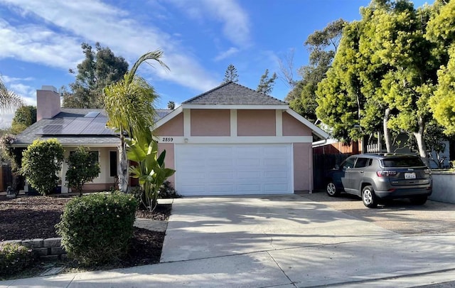 view of front facade with stucco siding, an attached garage, solar panels, and driveway