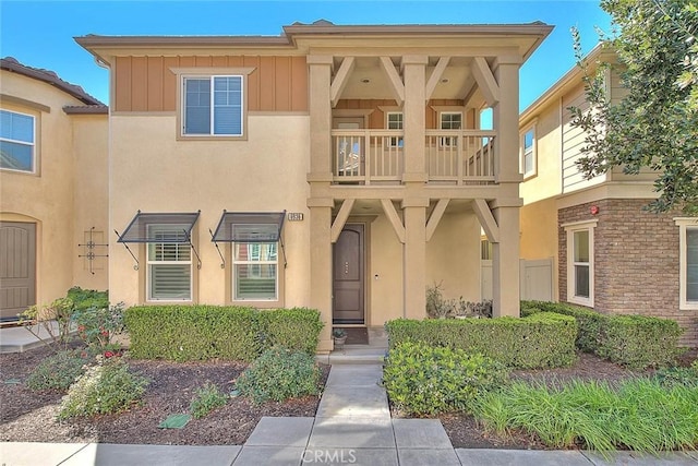 multi unit property with stucco siding, a balcony, and board and batten siding