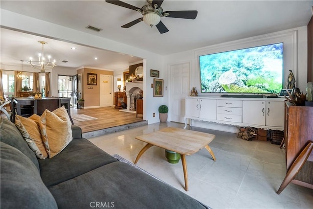 living room featuring recessed lighting, visible vents, ceiling fan with notable chandelier, and a fireplace with raised hearth
