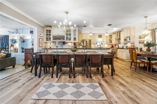 dining space featuring crown molding, a notable chandelier, and light wood finished floors