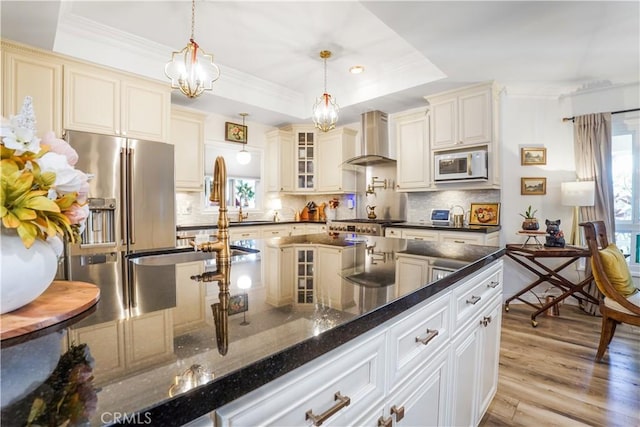 kitchen featuring a raised ceiling, white microwave, wall chimney exhaust hood, and ornamental molding