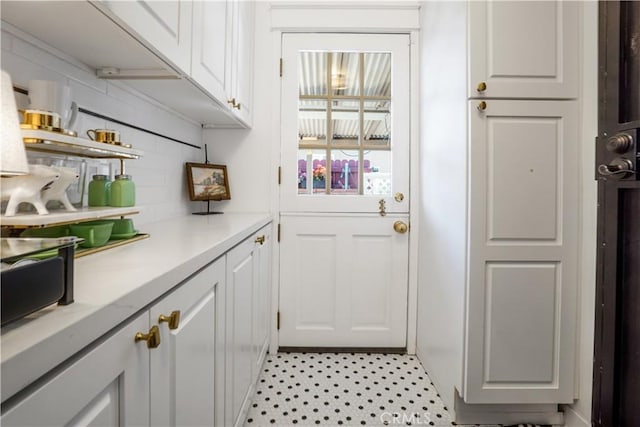 kitchen featuring decorative backsplash, white cabinetry, light floors, and light countertops