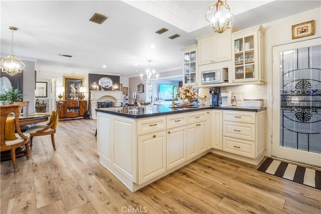 kitchen featuring cream cabinets, an inviting chandelier, and light wood-style flooring