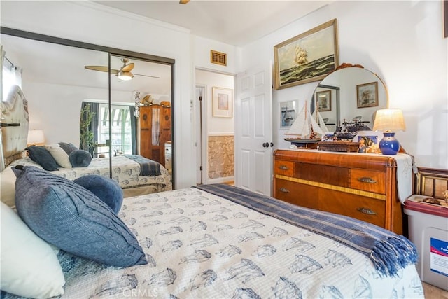 bedroom featuring a wainscoted wall, visible vents, a closet, and ceiling fan