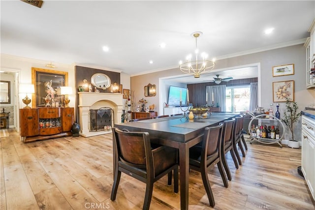 dining space featuring recessed lighting, a large fireplace, an inviting chandelier, crown molding, and light wood finished floors