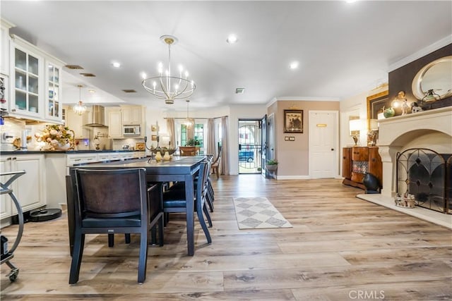 kitchen featuring white microwave, an inviting chandelier, a fireplace with raised hearth, dark countertops, and wall chimney range hood