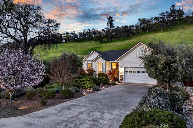 ranch-style house featuring board and batten siding, an attached garage, a front lawn, and concrete driveway