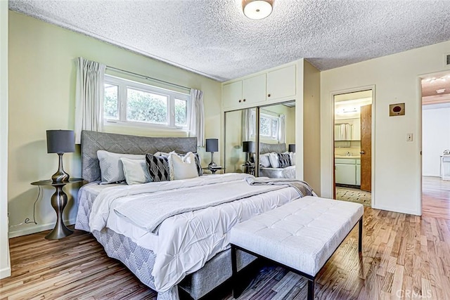 bedroom with baseboards, light wood finished floors, a sink, a closet, and a textured ceiling