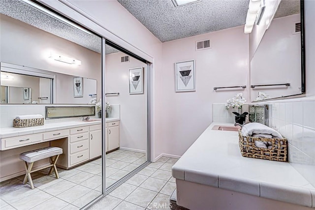 bathroom featuring visible vents, tasteful backsplash, vanity, and a textured ceiling