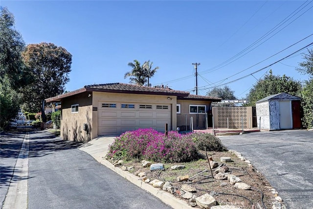 view of front of home featuring an outbuilding, stucco siding, a storage unit, and fence