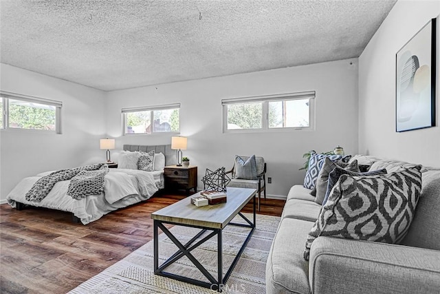 bedroom featuring multiple windows, a textured ceiling, and wood finished floors