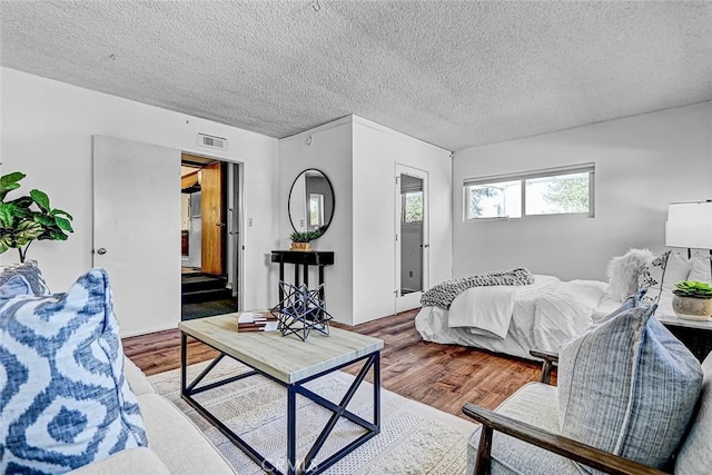 bedroom featuring visible vents, a textured ceiling, and wood finished floors