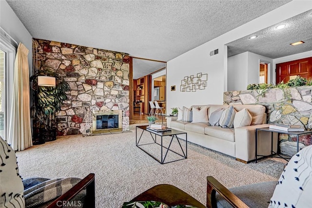 living room featuring visible vents, carpet flooring, a fireplace, and a textured ceiling