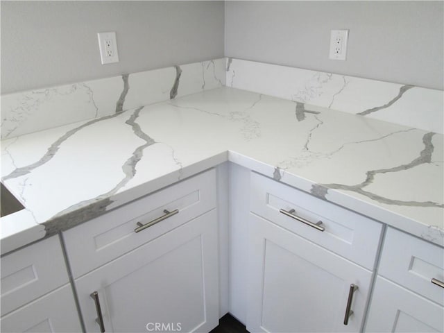 room details with white cabinetry and light stone counters