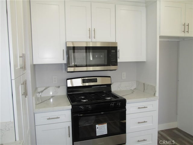 kitchen featuring baseboards, light stone counters, wood finished floors, white cabinets, and stainless steel appliances