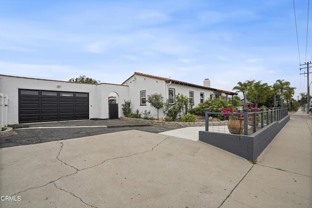 mediterranean / spanish house featuring stucco siding, driveway, fence, an attached garage, and a tiled roof